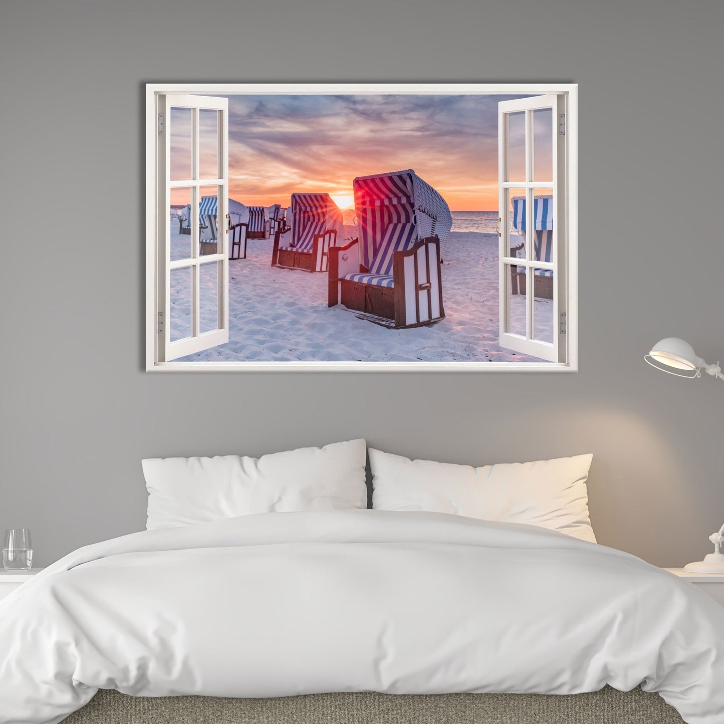 Wandbild mit offenem Fensterblick auf einen Sandstrand mit blau-weiß gestreiften Strandkörben beim Sonnenuntergang. Das warme Licht spiegelt sich auf dem weißen Sand und erzeugt eine beruhigende Atmosphäre. Perfekt als stilvolle Wanddekoration für Schlafzimmer oder Wohnzimmer.