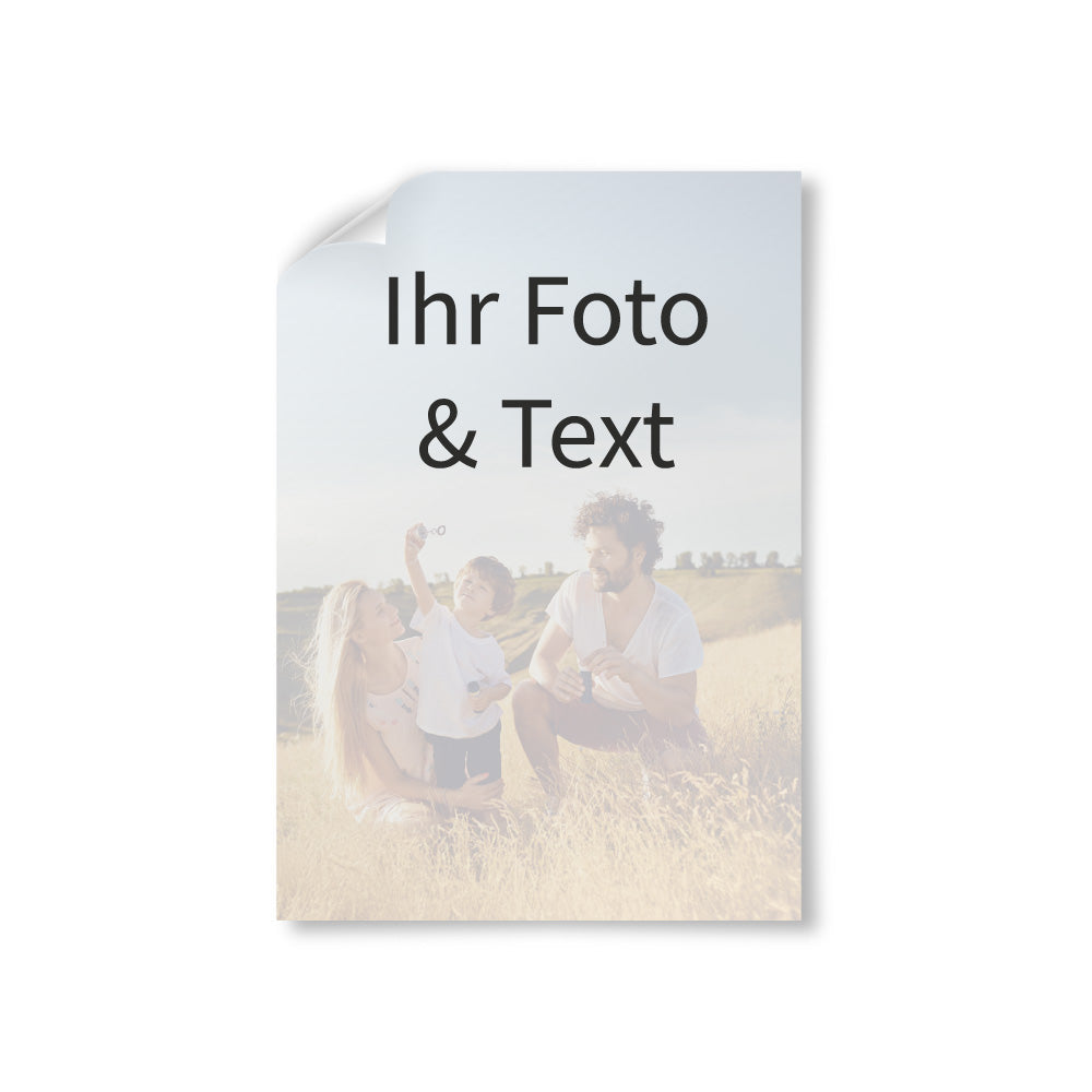 Vorschau eines personalisierbaren Posters mit eigenem Foto und Text. Das Beispielmotiv zeigt eine Familie auf einer Wiese. Die obere Ecke des Posters ist leicht umgeklappt, um die Papierstruktur darzustellen. Ideal für individuelle Wanddekoration oder als Geschenk.
