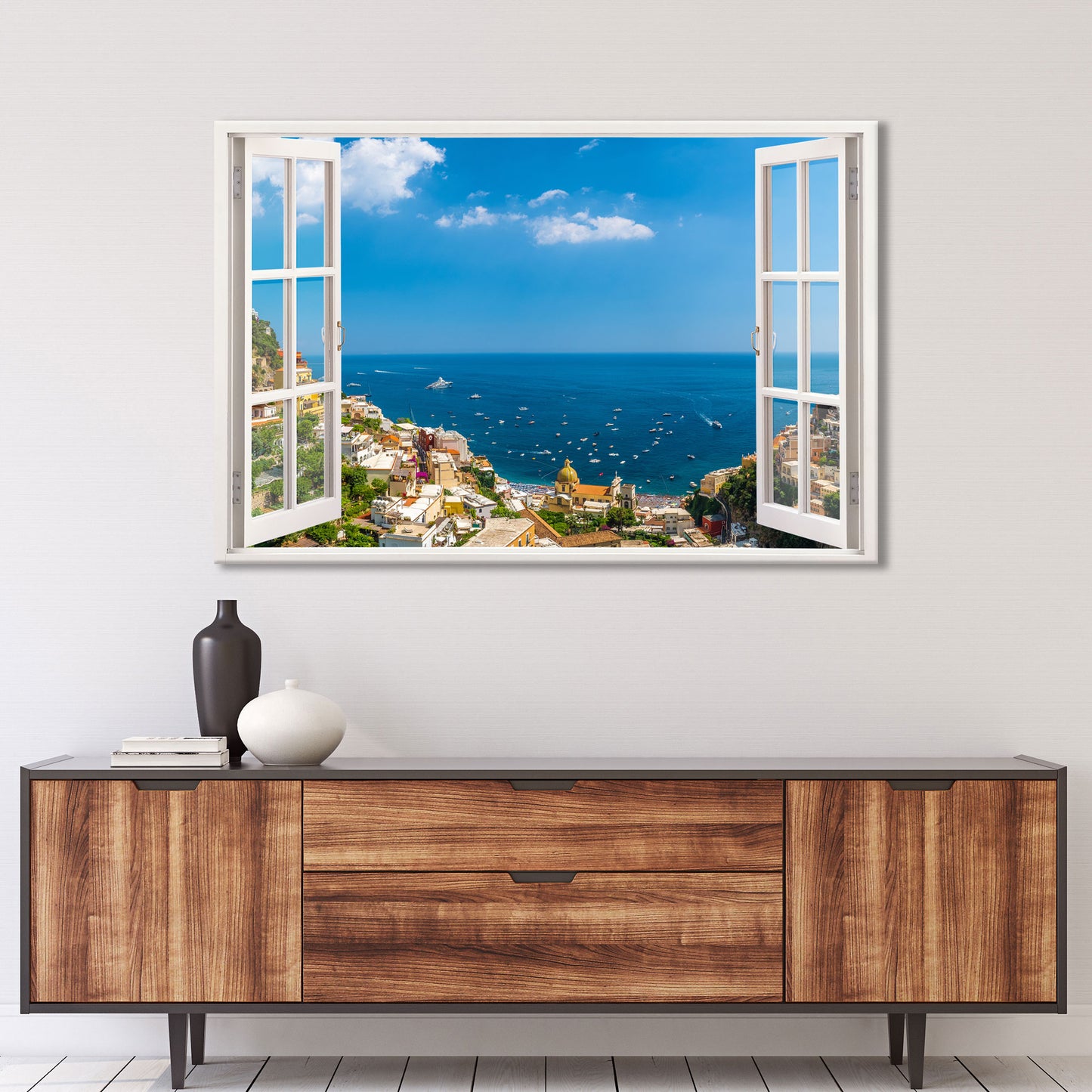 Ein realistisches Wandtattoo mit einem offenen Fensterblick auf eine malerische italienische Küstenstadt. Die Szene zeigt Positano an der Amalfiküste mit seinen bunten Häusern, einer kleinen Kirche und zahlreichen Booten, die auf dem tiefblauen Mittelmeer treiben. Der Himmel ist strahlend blau mit leichten Wolken. Das Wandbild verleiht dem Raum ein Gefühl von Weite und Urlaubsflair. Perfekt für eine entspannte und stilvolle Wohnatmosphäre.