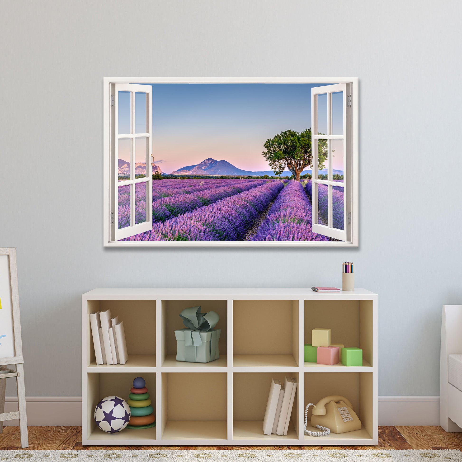 Wandbild mit offenem Fensterblick auf ein weitläufiges Lavendelfeld in der Provence bei Sonnenuntergang. Die violetten Reihen führen zu einem markanten Baum, mit Bergen im Hintergrund und einem sanften Abendhimmel. Perfekte Wanddekoration für ein beruhigendes Ambiente.