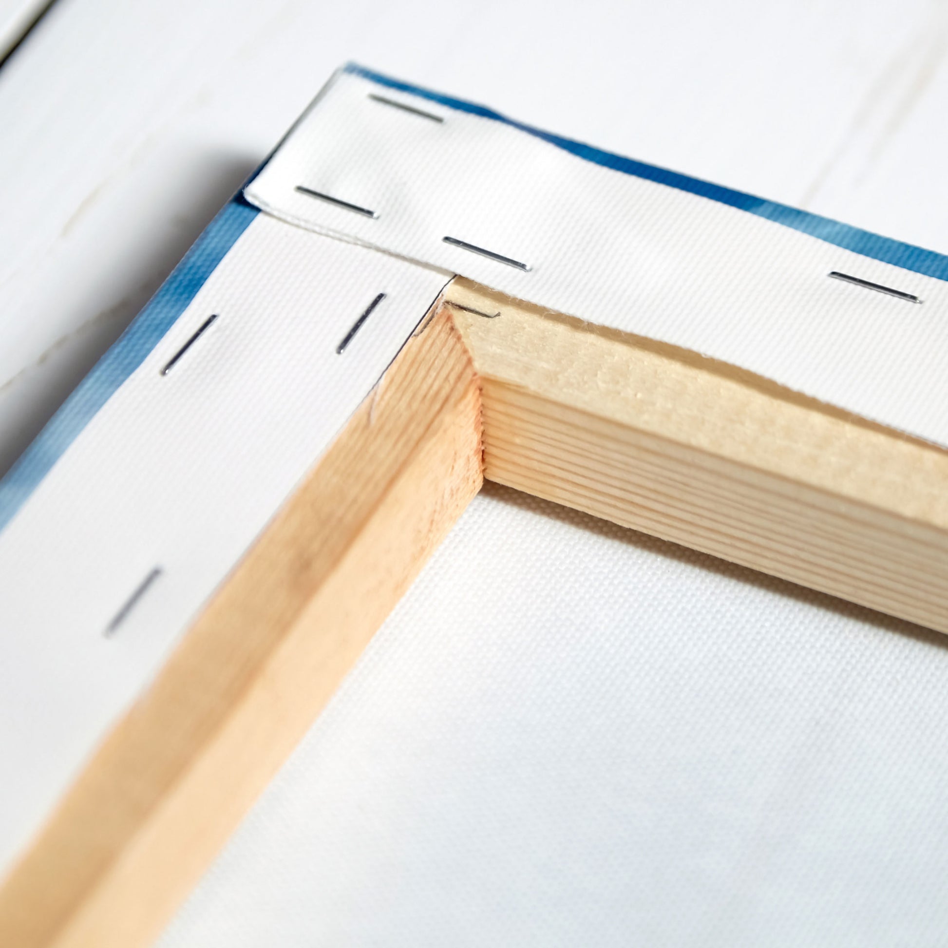 Nahaufnahme der Rückseite eines Leinwandbildes mit stabiler Holz-Keilrahmenkonstruktion. Die Leinwand ist präzise gespannt und mit Klammern befestigt, was für eine langlebige und hochwertige Verarbeitung sorgt.