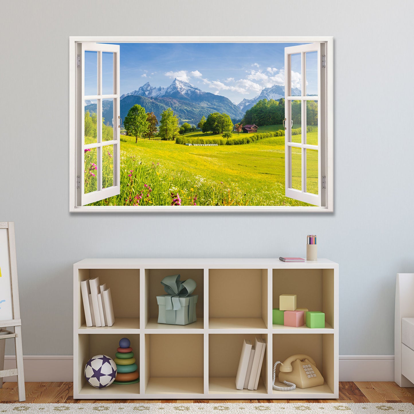 Leinwandbild mit offenem Fensterblick auf eine sonnige Berglandschaft mit grünen Wiesen und schneebedeckten Gipfeln, stilvoll integriert in ein gemütliches Kinderzimmer mit Regal und Spielzeug. Perfekte Wanddekoration für ein harmonisches Wohnambiente.